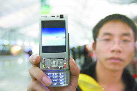 机上乘客向记者展示用手机拍到的左机翼下冒烟的图片。